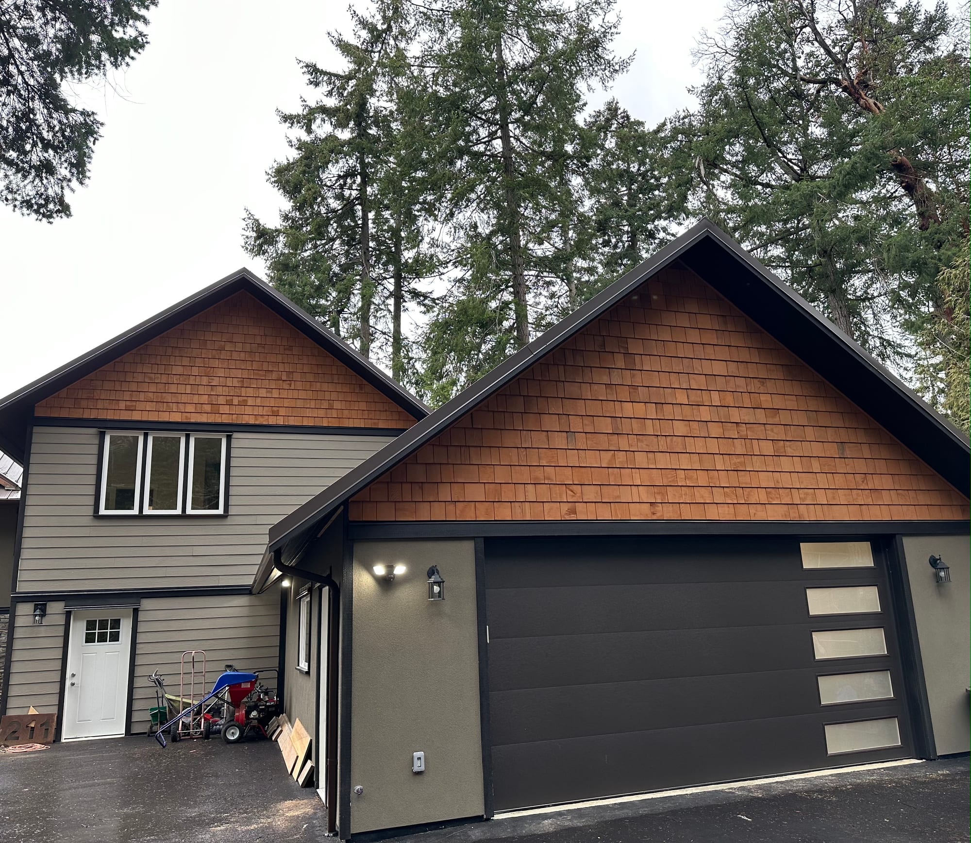 Completed two-storey addition — cedar shake gable, double-car garage and charcoal insulated door with glass panels