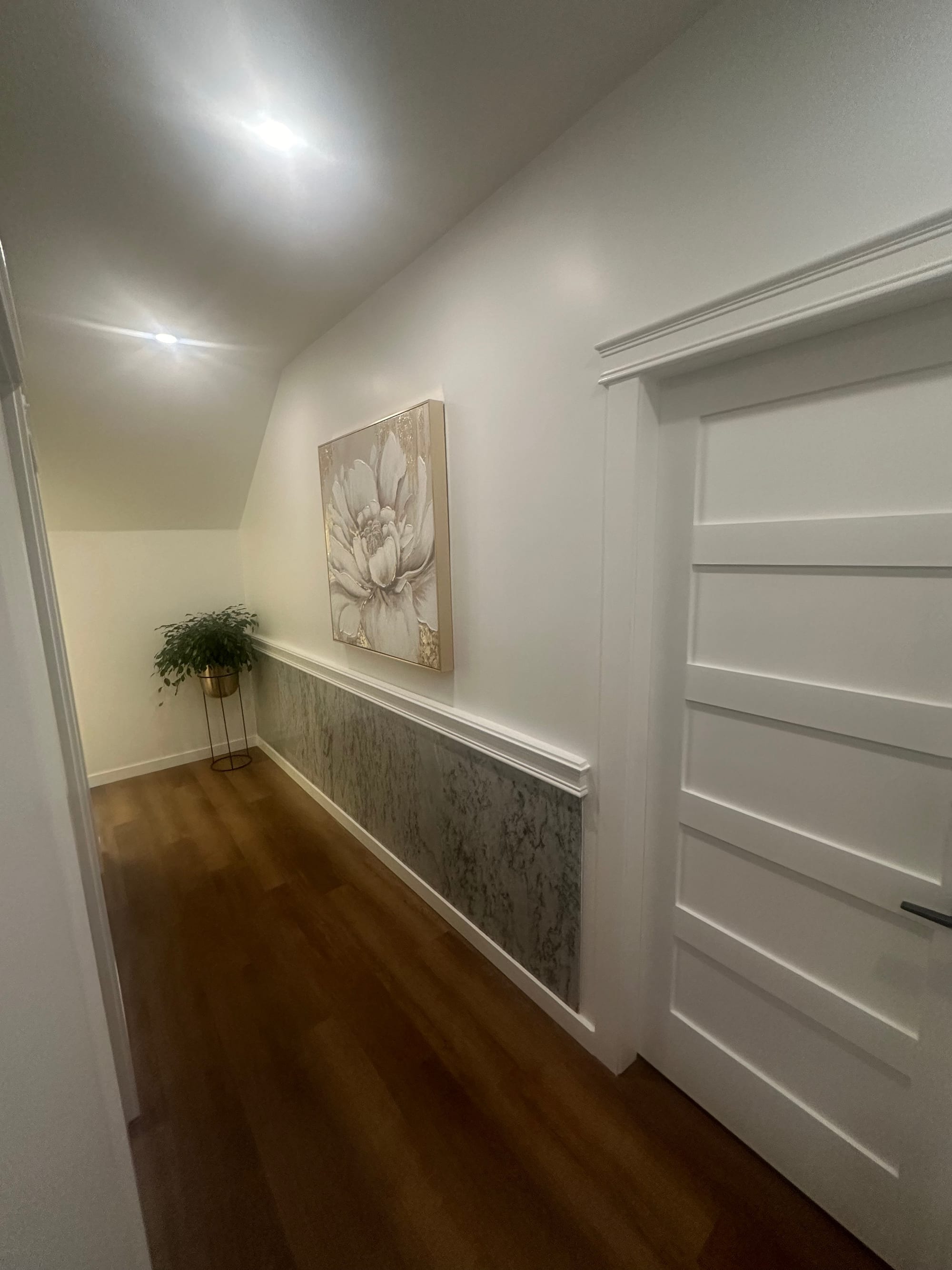 Corridor within the completed Samya Spa commercial renovation — stone-patterned wainscot, hardwood floor and panelled trim