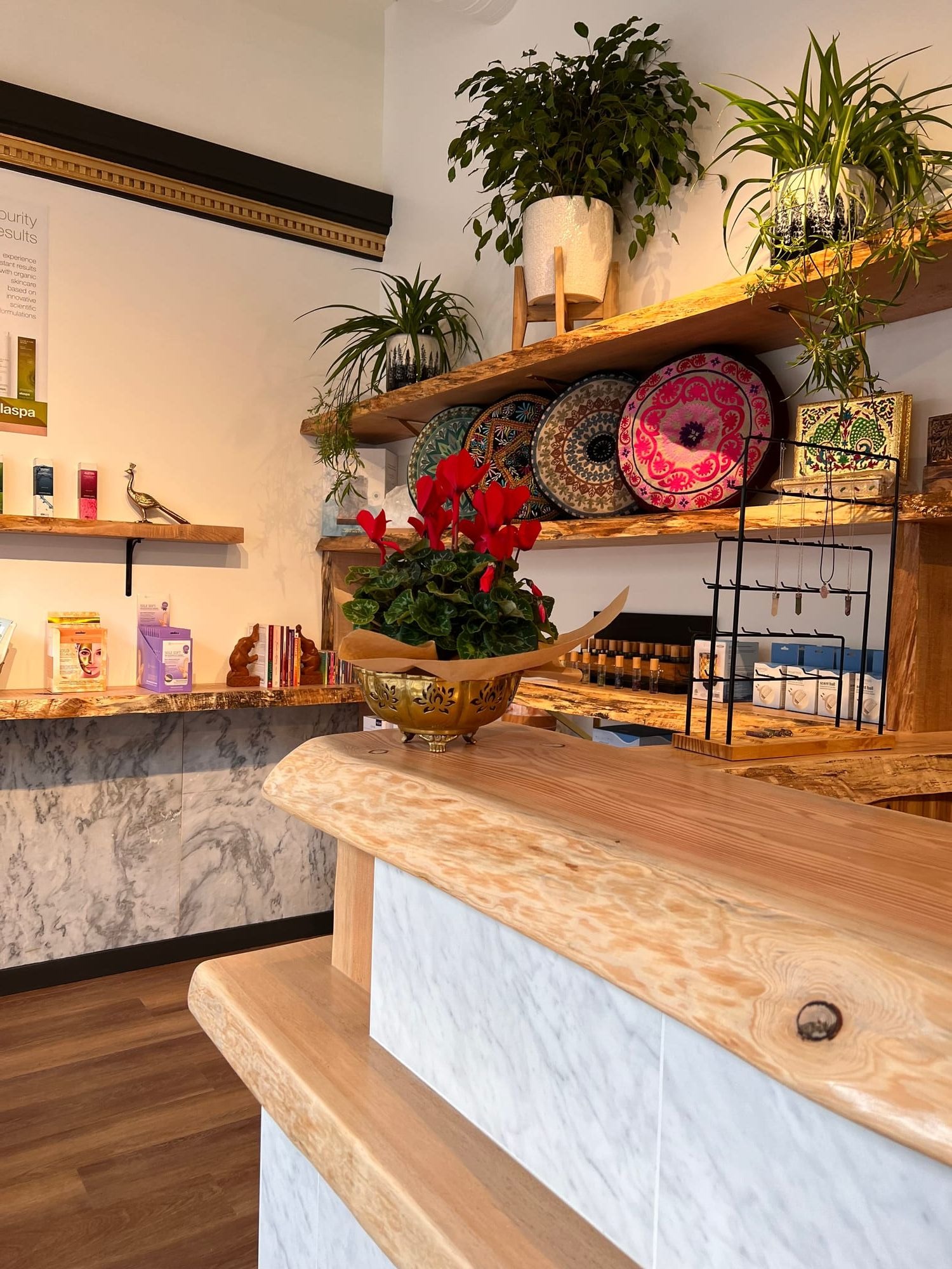 Reception counter detail with live-edge wood top, stone-look cladding and retail display shelving