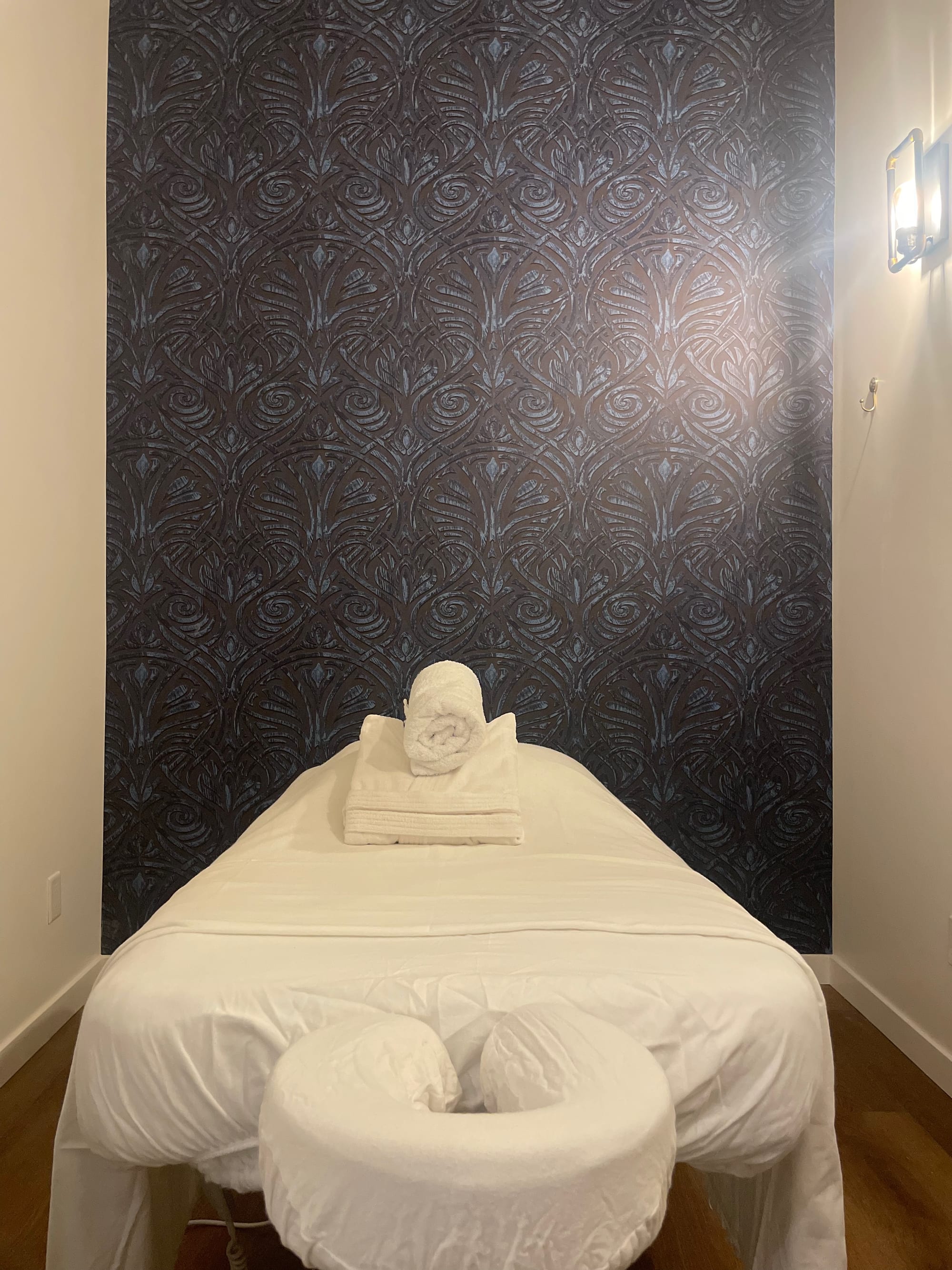 Dry treatment room with dark embossed Art Deco feature wall and hardwood flooring
