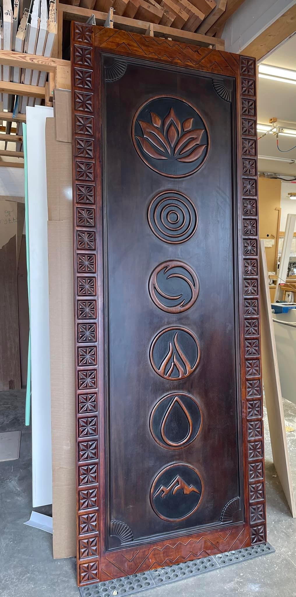Completed dark-stained carved entry panel in the workshop before installation