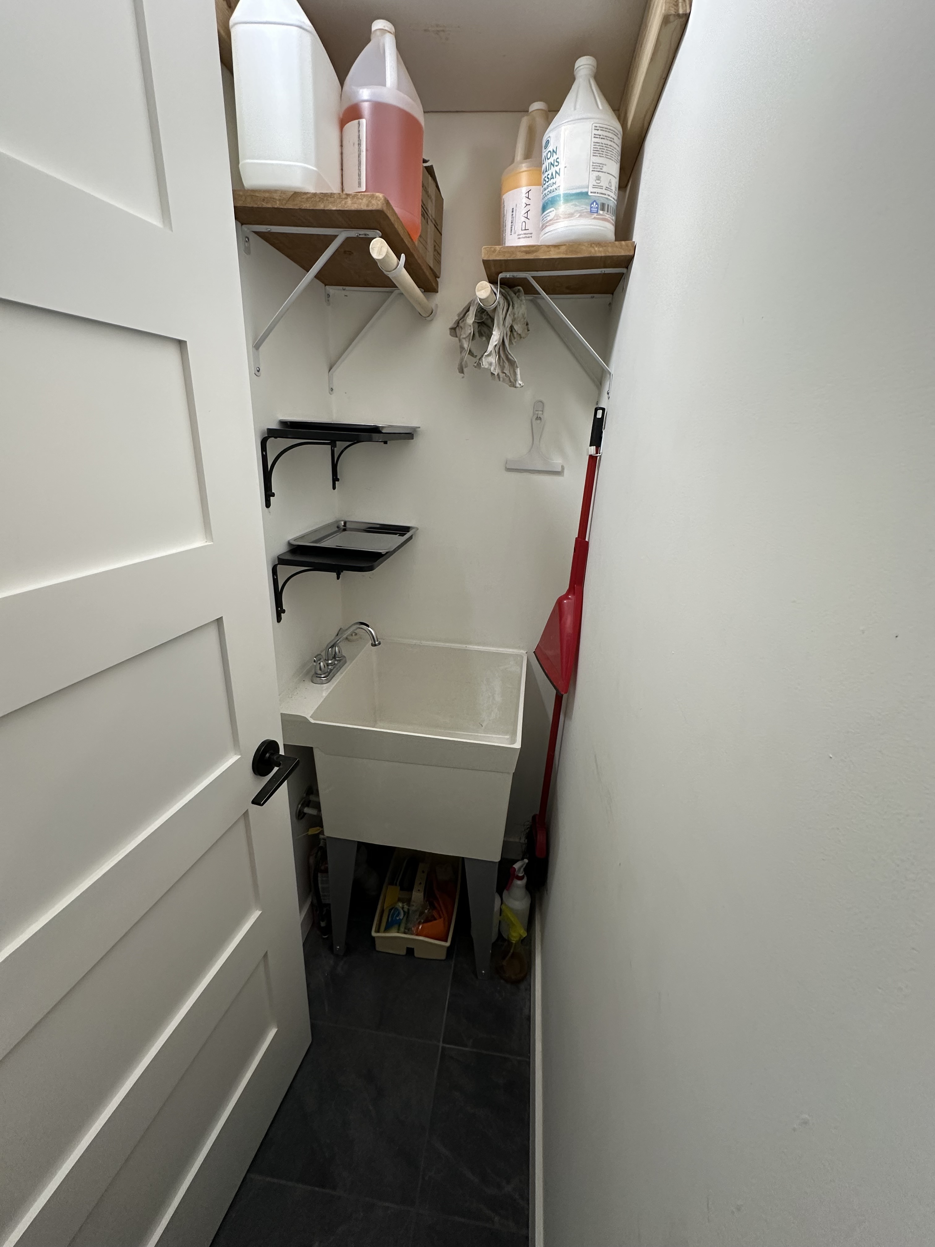 Completed compact laundry and cleaning room with utility sink and storage shelves