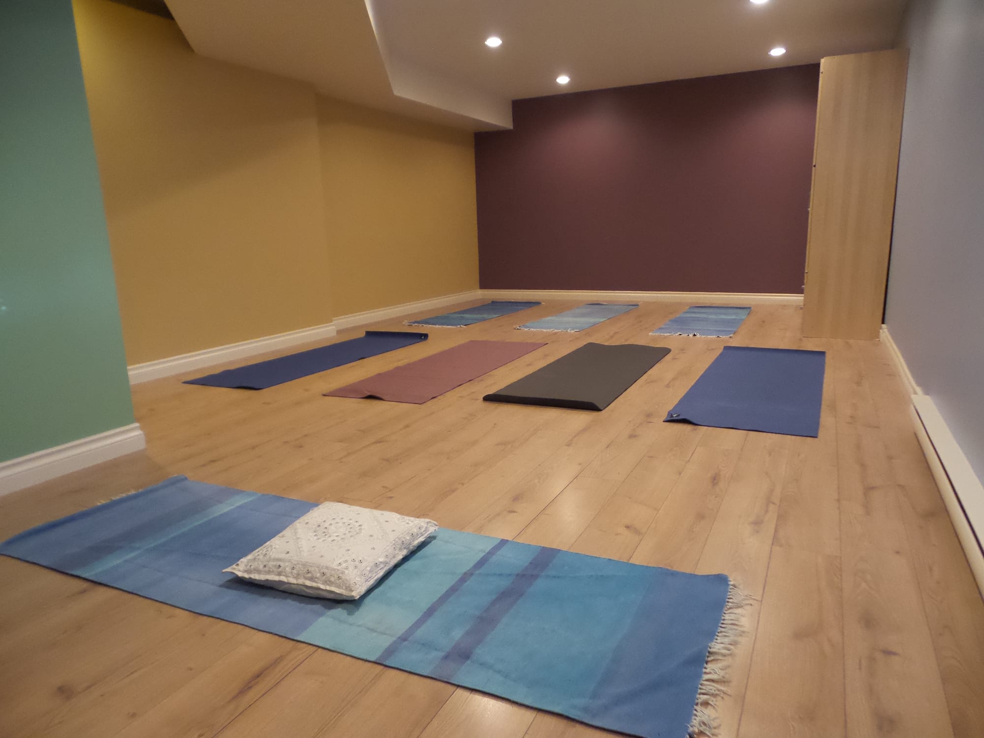 Completed commercial yoga studio with wood flooring, recessed lighting and yoga mats