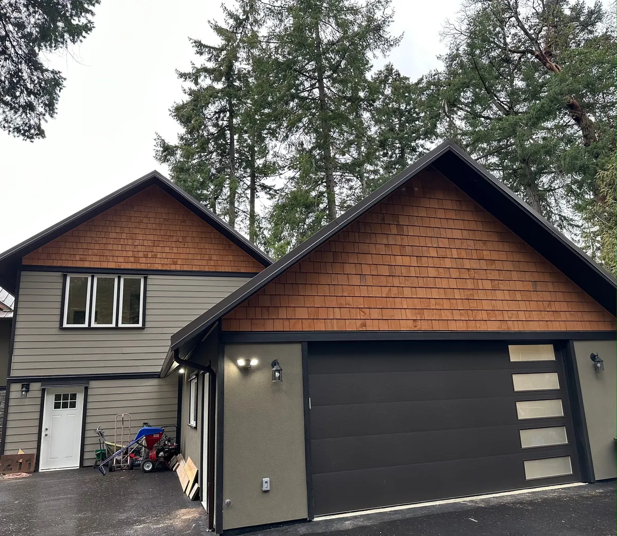Completed two-storey addition — cedar shake gable, double-car garage and charcoal insulated door with glass panels