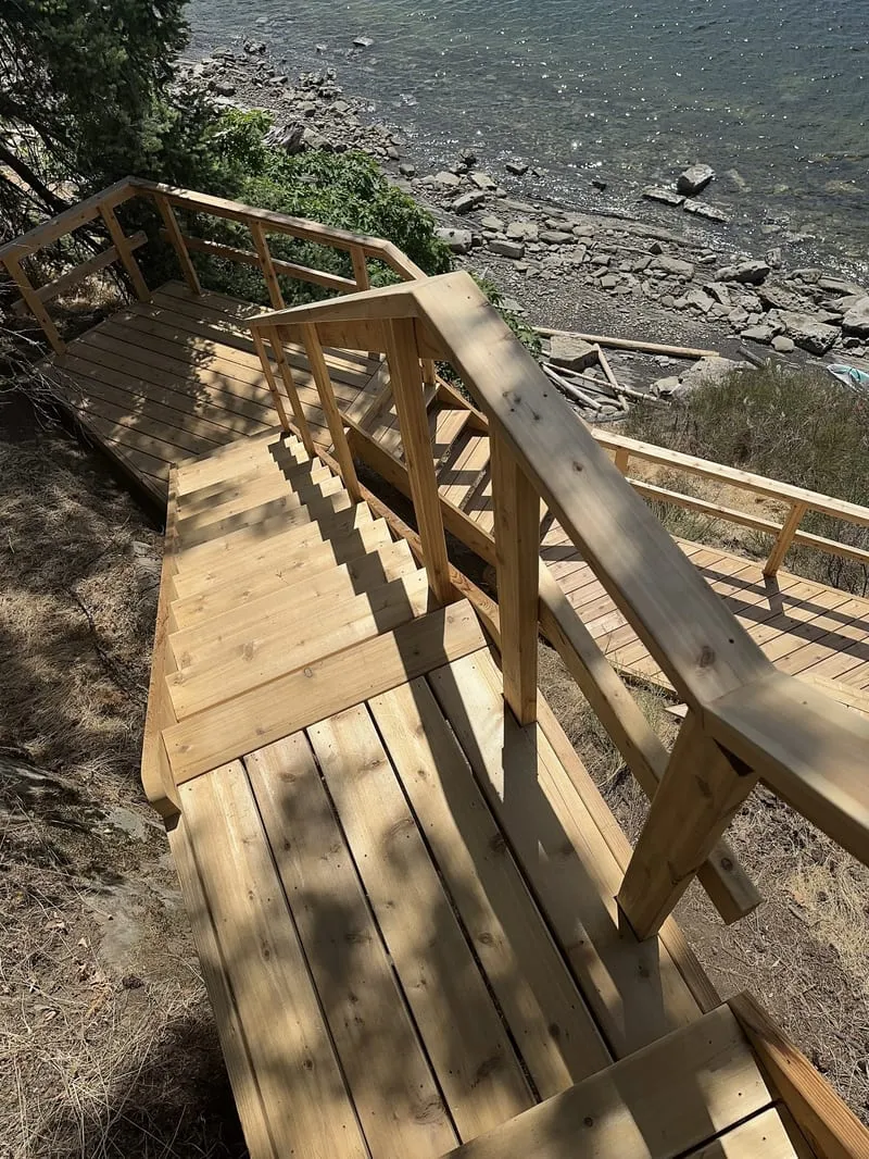 Cedar stair and walkway system descending a steep coastal slope to the shoreline
