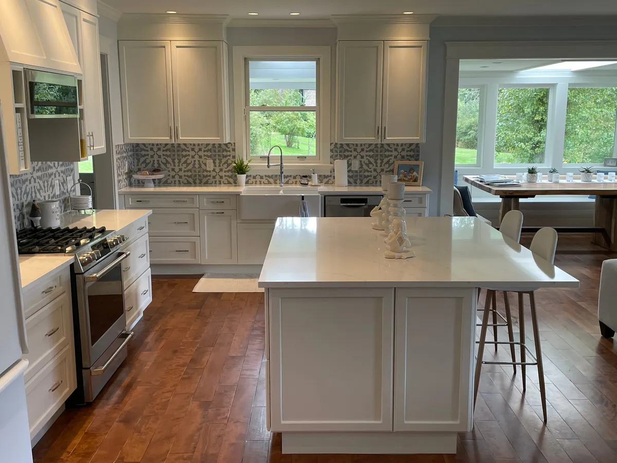 Completed kitchen renovation — white shaker cabinetry, quartz island and patterned tile backsplash