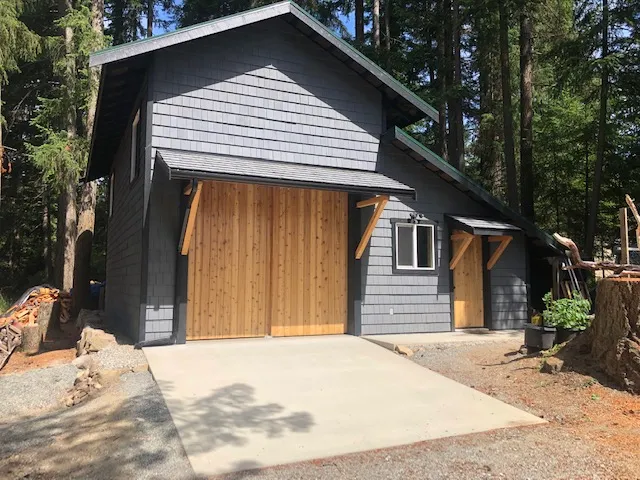 Completed enclosed workshop with custom cedar doors, exterior cladding and concrete apron