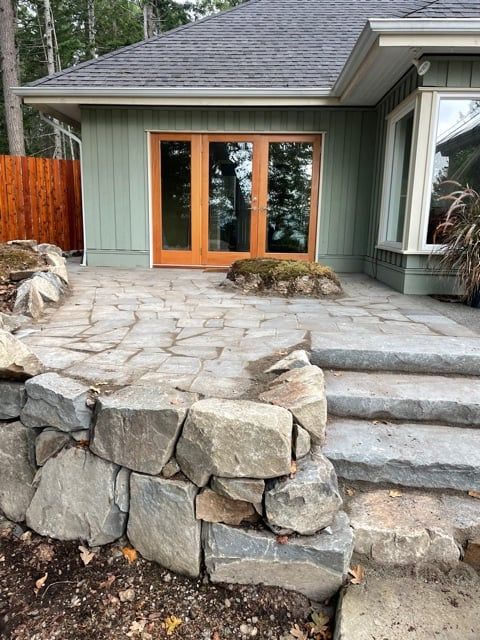 Completed stone patio, steps and retaining wall leading to cedar doors