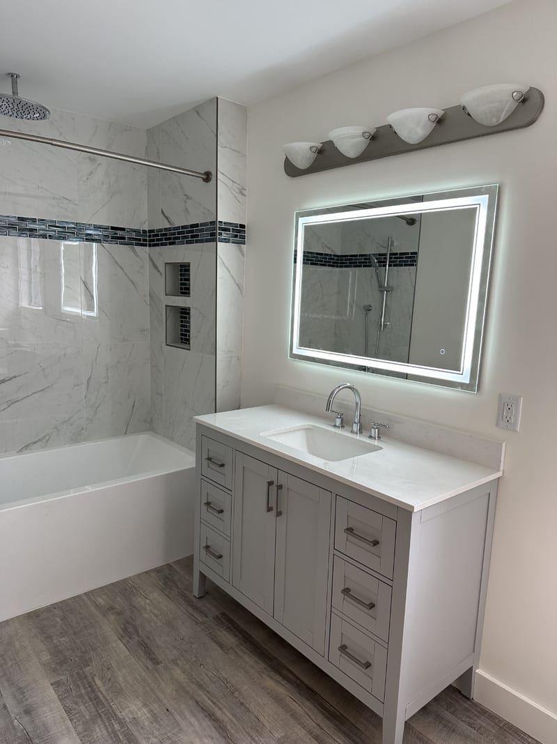 White vanity and tub-and-shower surround with dark accent band