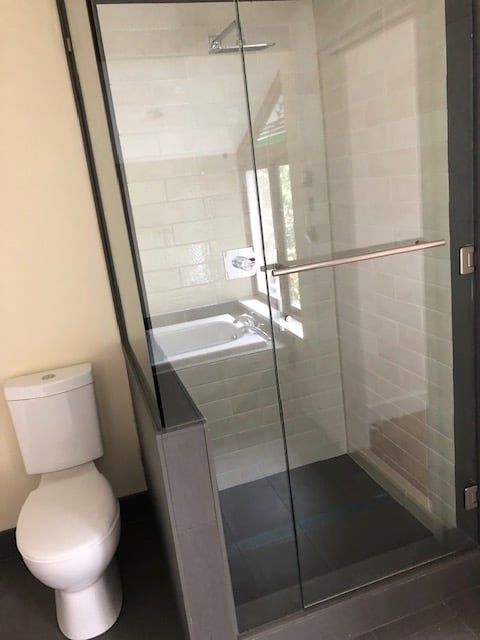 Bathroom with warm wood cabinetry, built-in tub and glass shower