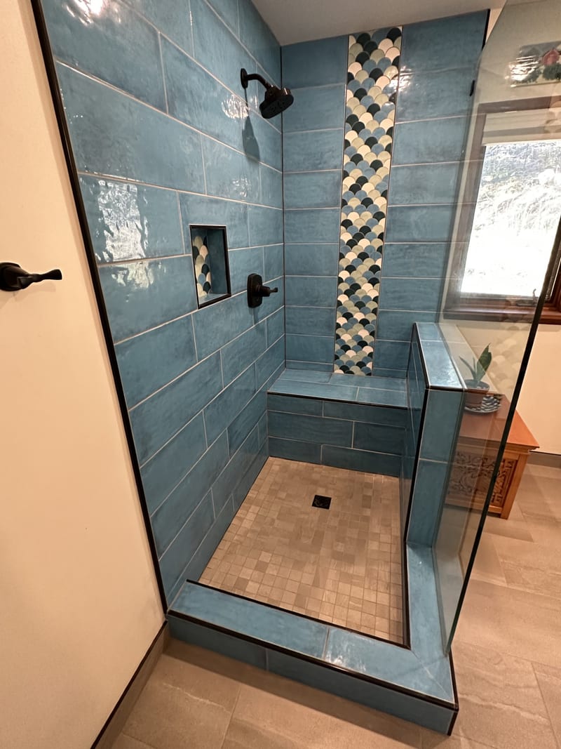 Walk-in shower — blue glazed tile, scallop accent strip, integrated bench, frameless glass