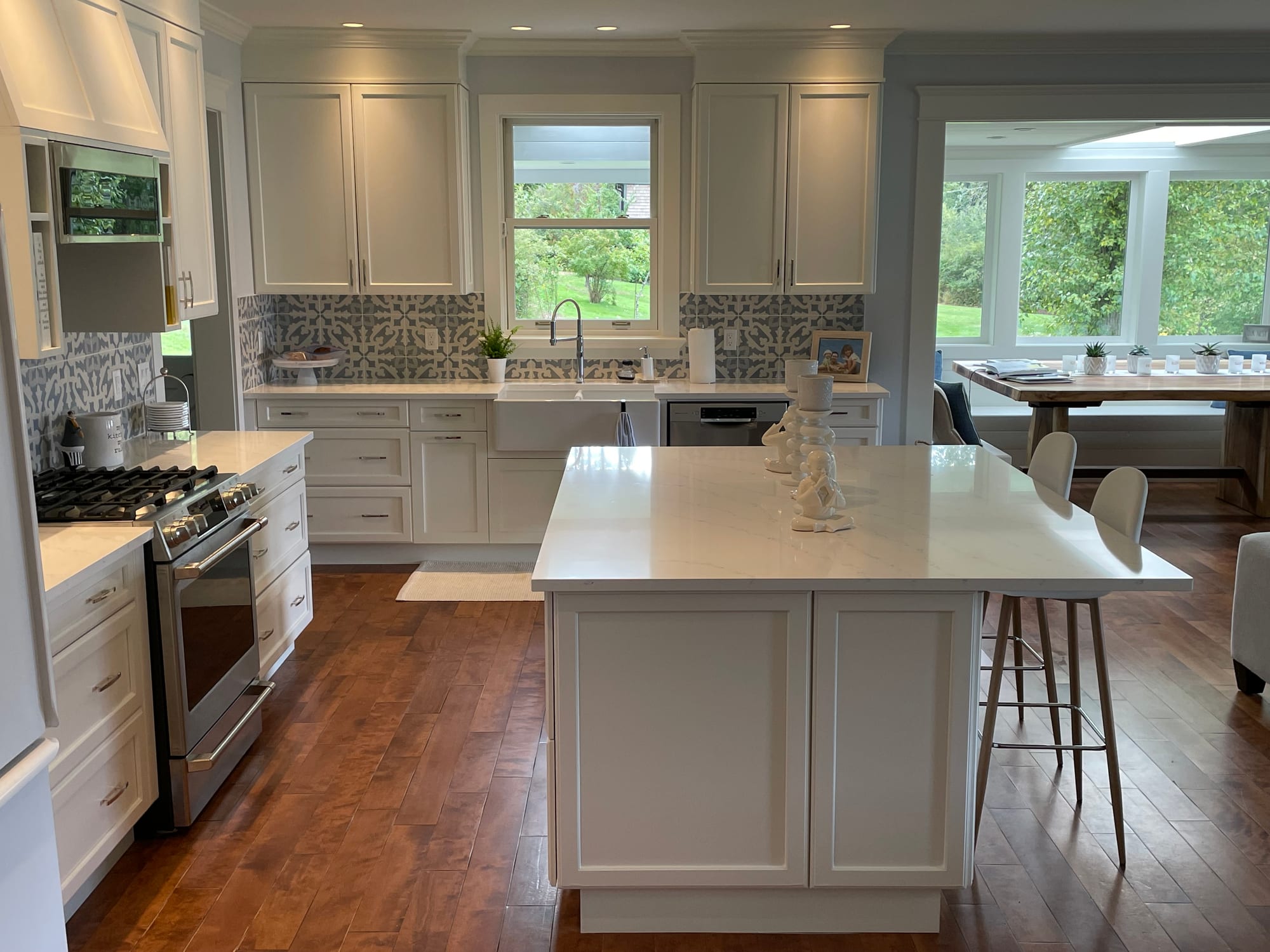 Completed kitchen renovation — white shaker cabinetry, quartz island and patterned tile backsplash