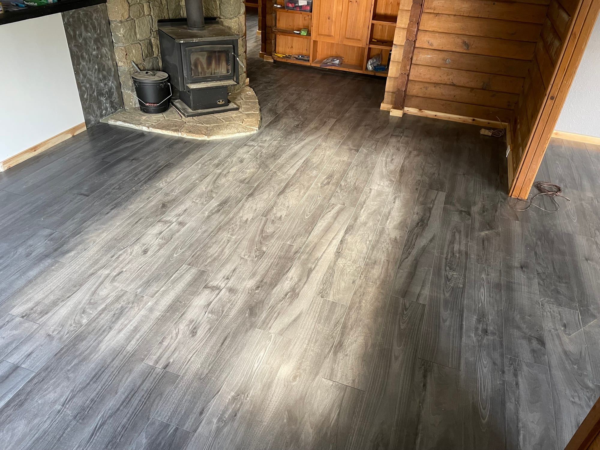 Character log home renovation — new flooring and wood stove within established timber structure