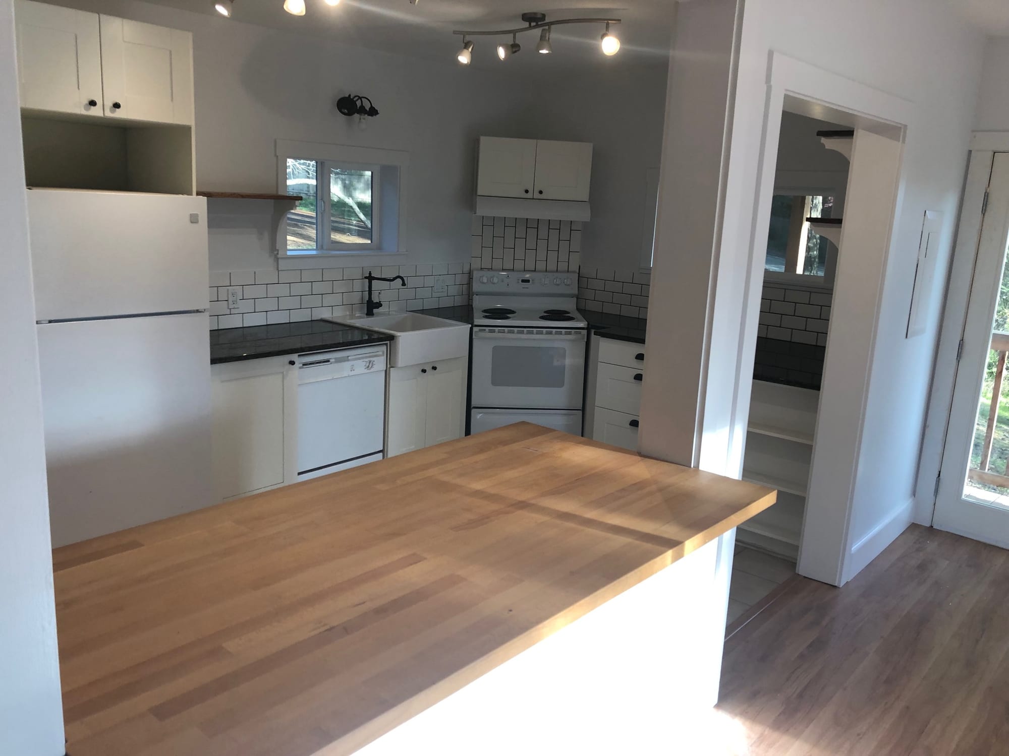 Red cabin kitchen renovation — white cabinetry, butcher block peninsula, subway tile backsplash